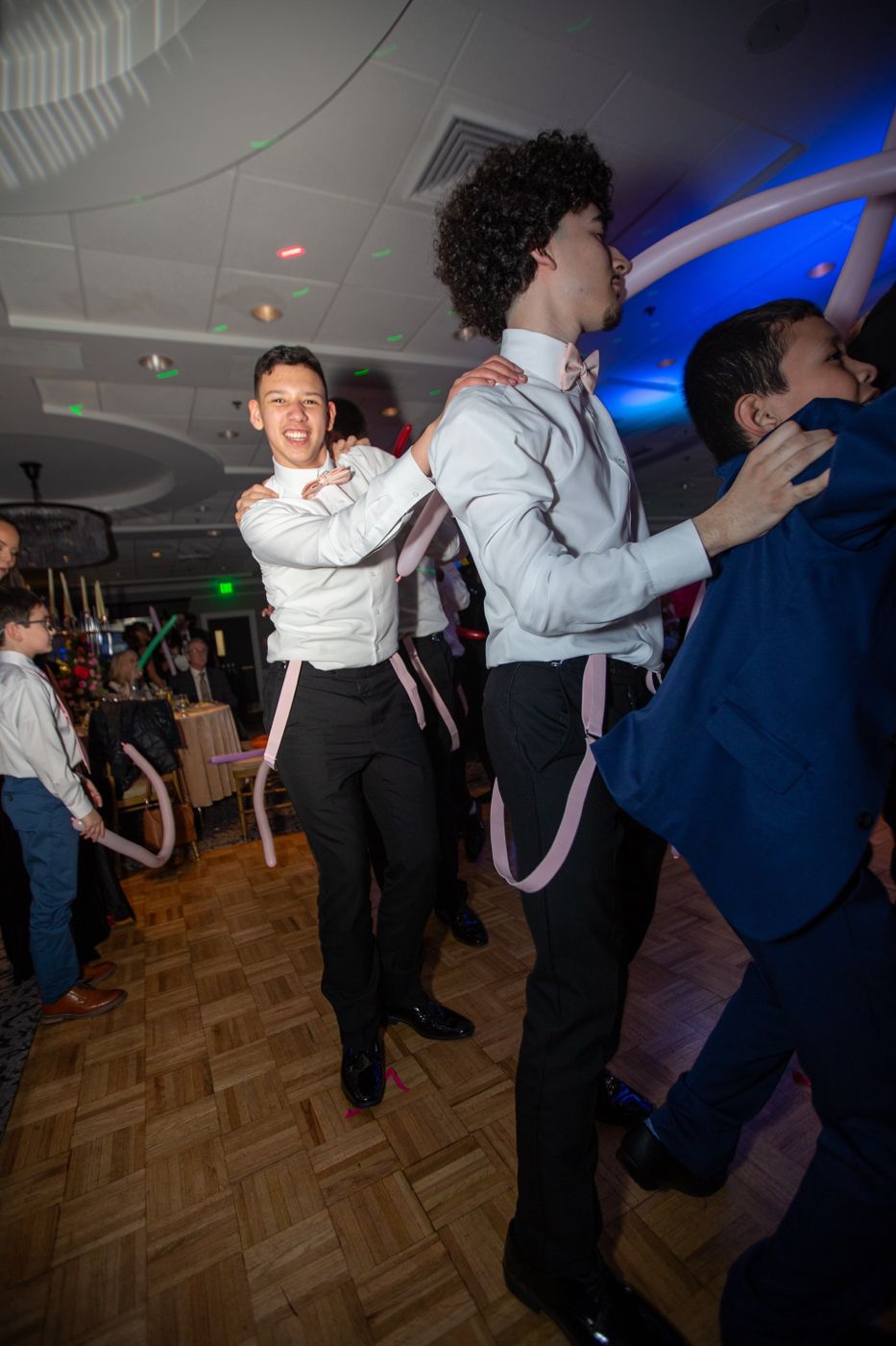 Guests in pink bow ties and suspenders dancing together