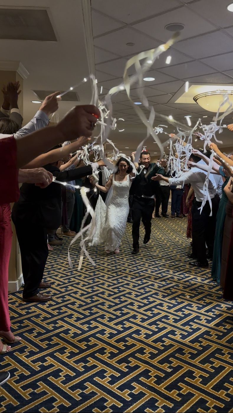 Couple running through a ribbon and light-wand grand exit