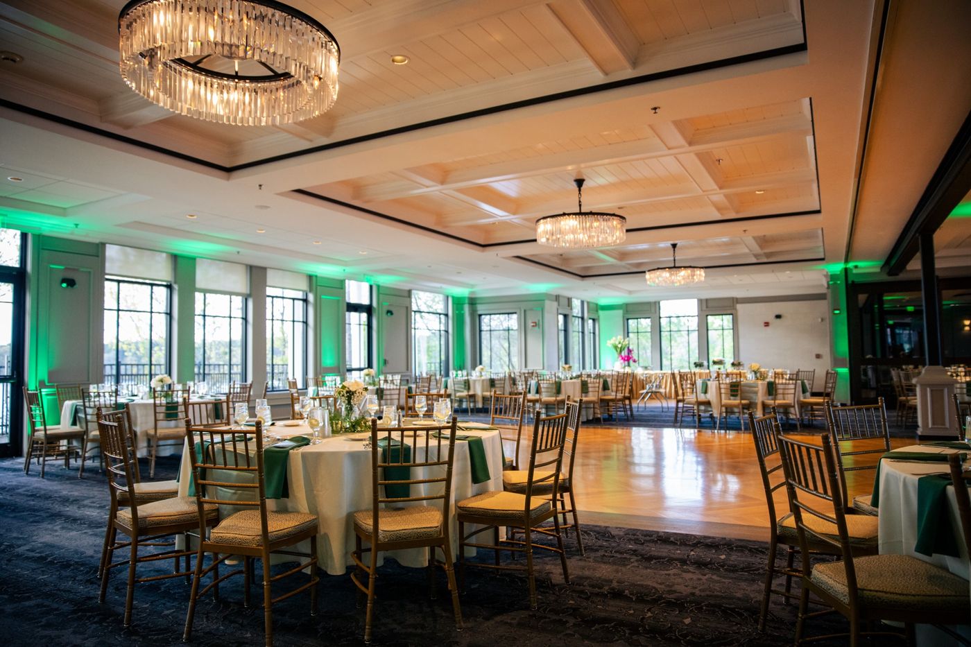 A ballroom with green uplighting and an open dance floor